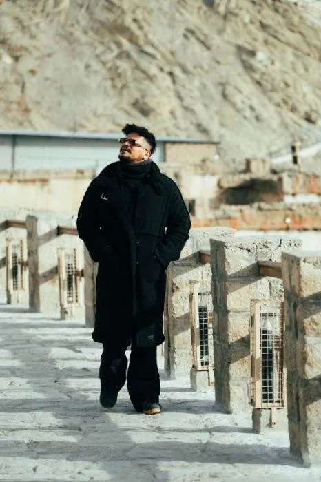 Avi Jaiswal in a black coat on a stone walkway